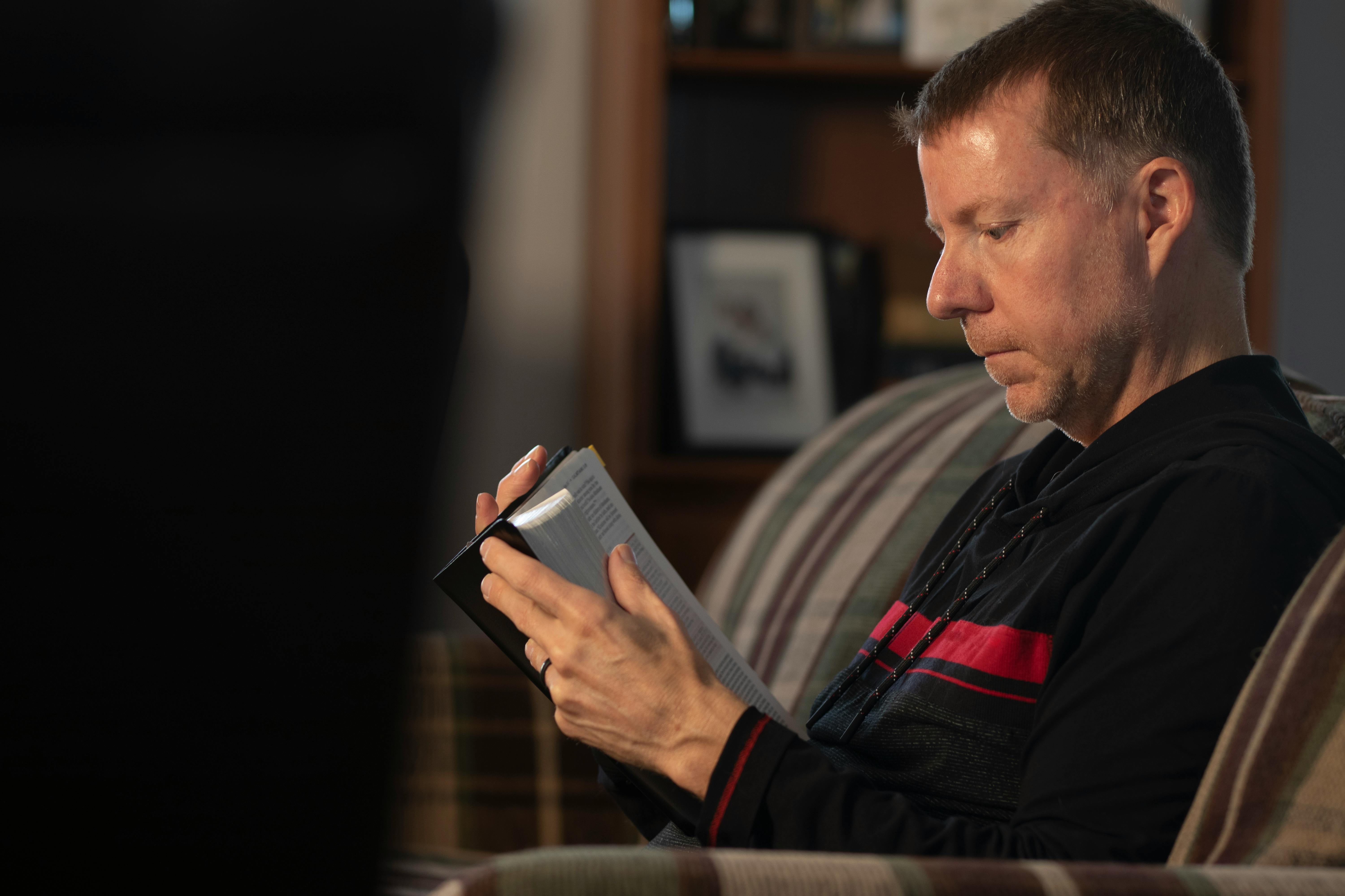 a man in black and red sweater holding a book