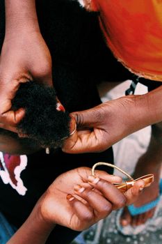 Close-up shot of hands styling afro hair with a ribbon in Nigeria.