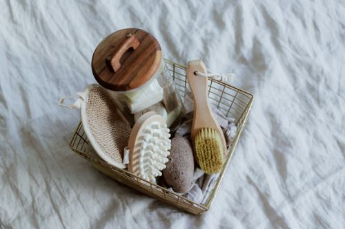 Free Flat lay of a spa basket containing brushes, mesh sponge, pumice stone, and a jar, perfect for at-home relaxation. Stock Photo