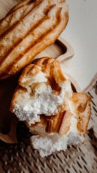 A delicious close-up of eclairs with creamy filling on a rustic wooden board.