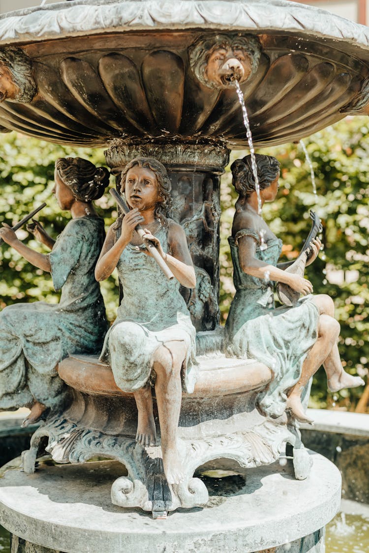 A Fountain With Statues Of Woman Playing Musical Instruments