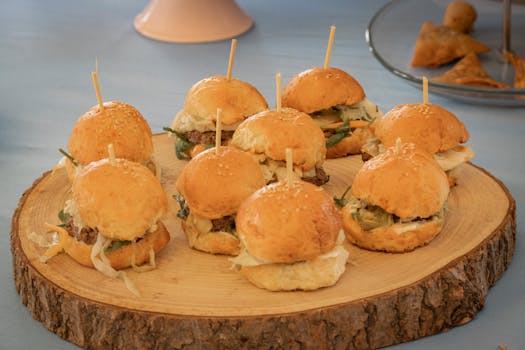 Tasty mini burgers served on a rustic wooden platter, perfect for party appetizers.