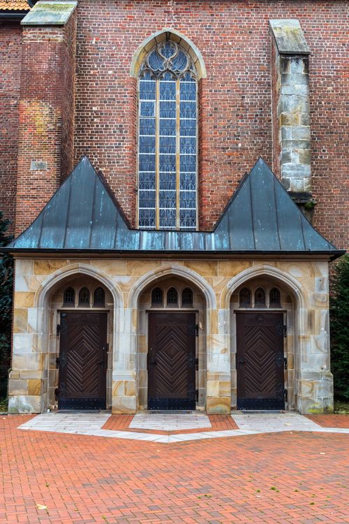 Free Capture of a vintage brick facade featuring Gothic-style arched doors and window. Stock Photo