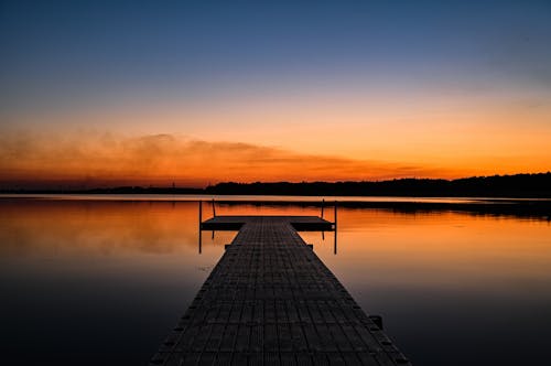 Black Dock on Calm Water during Sunset