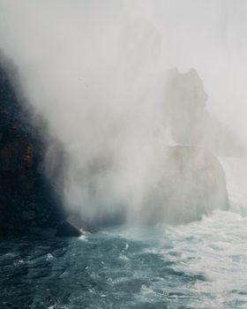 A breathtaking view of Niagara Falls with mist and rugged rocks creating a dramatic scene.
