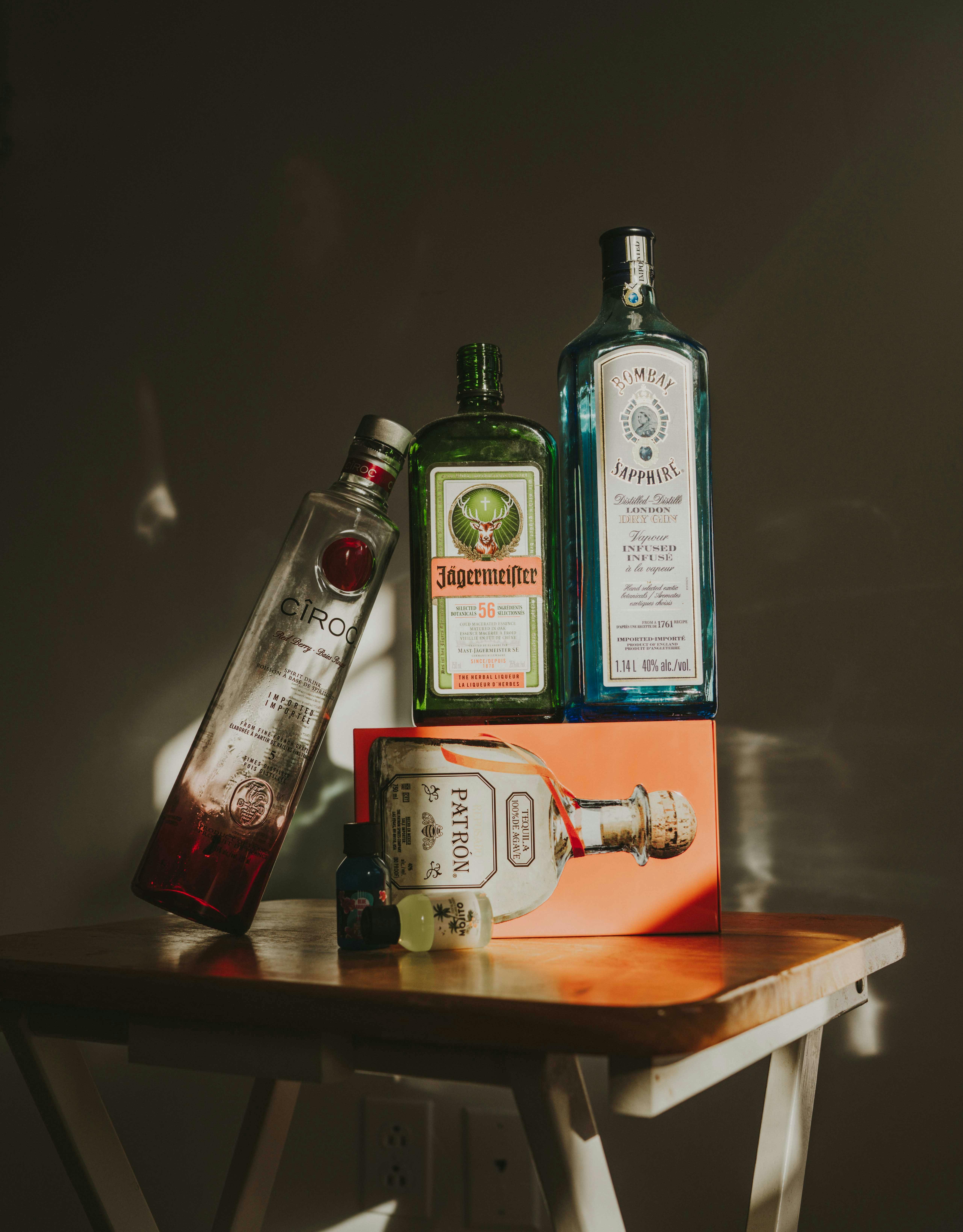 Vertical shot of assorted alcohol bottles on a wooden table showcasing various spirits.
