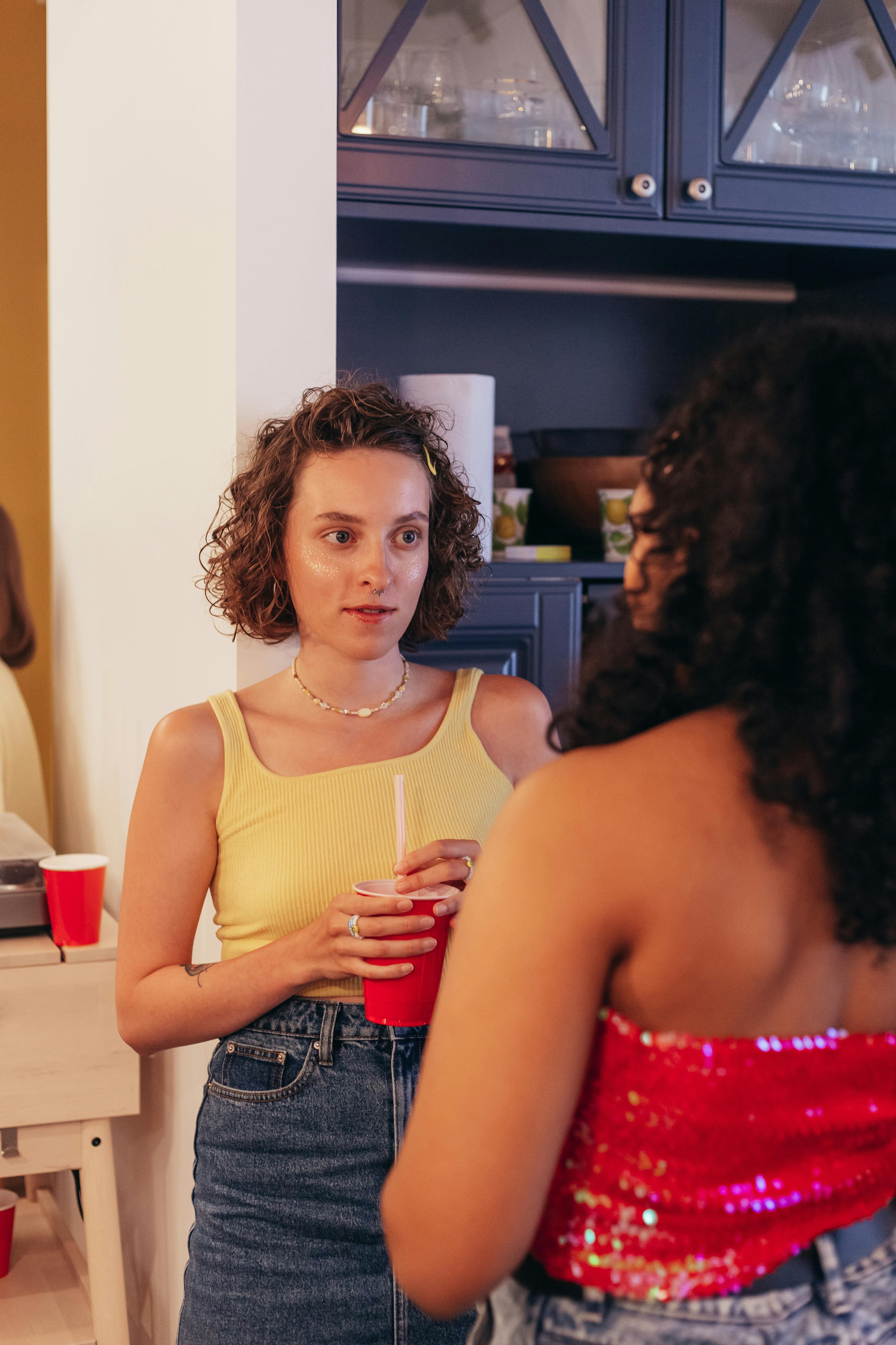 Two women having a friendly conversation at an indoor gathering.