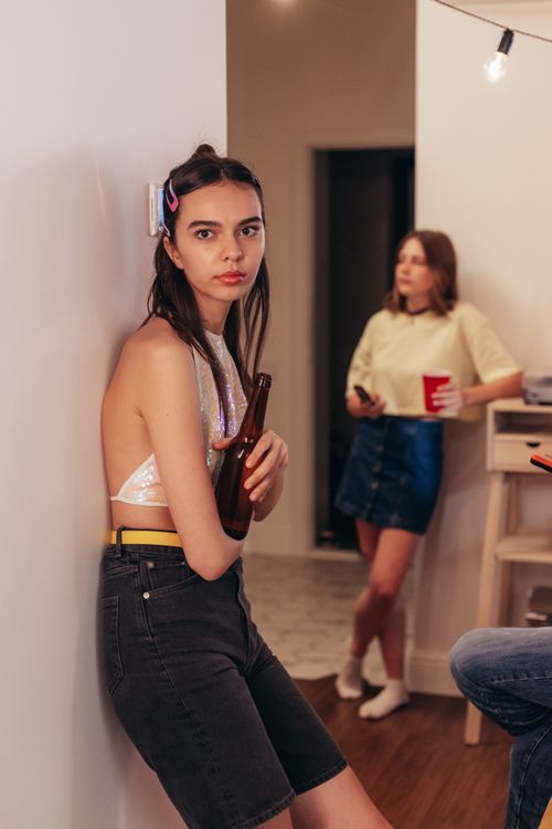 Free Young adults socializing at a casual house party, holding drinks and relaxing indoors. Stock Photo