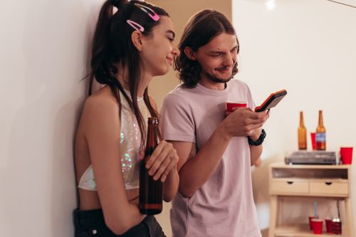 Free Two friends smiling and enjoying a casual indoor social gathering with drinks. Stock Photo
