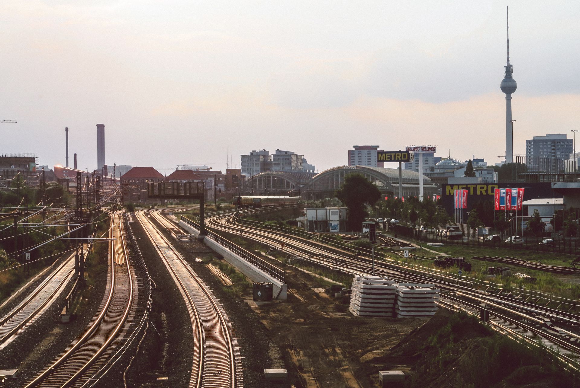 Urban railway in Berlin with TV tower visible at sunset, showcasing city transport.