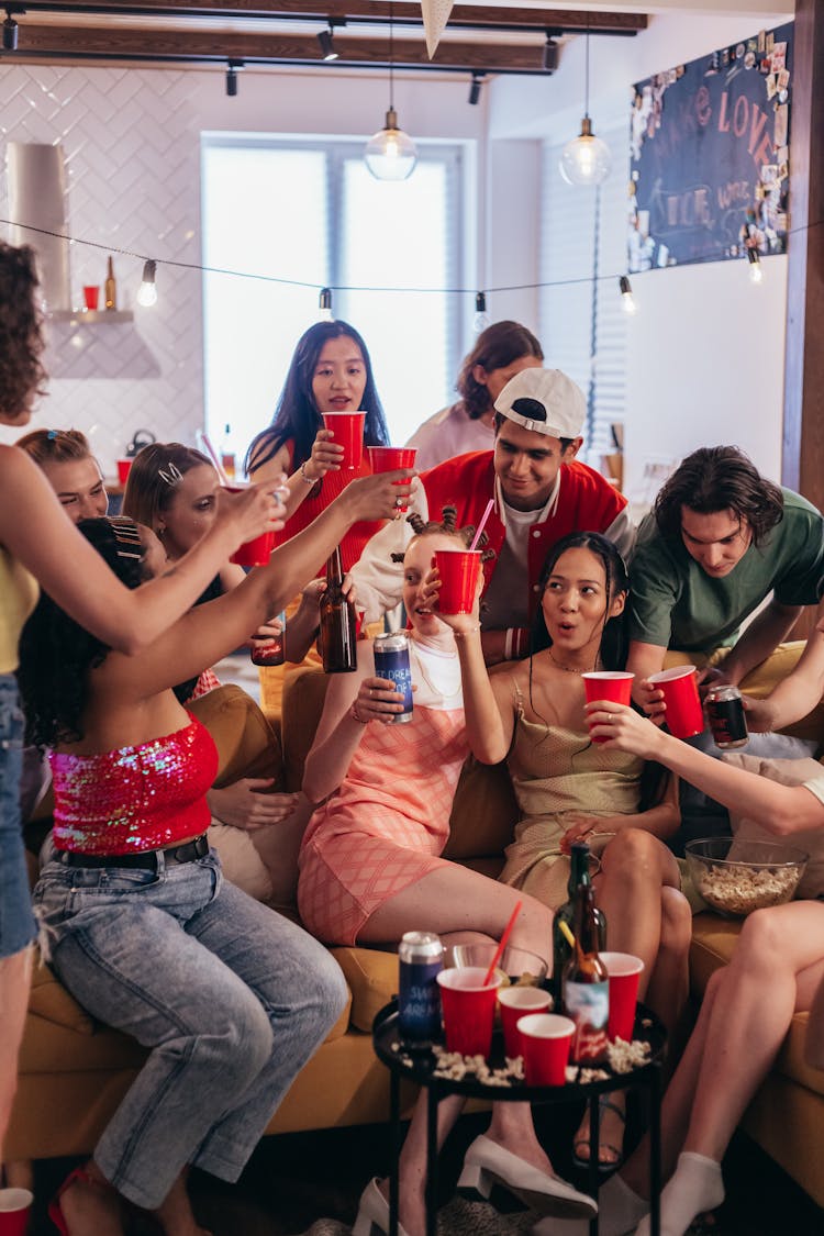 A Group Of People On A Couch Holding Red Cups