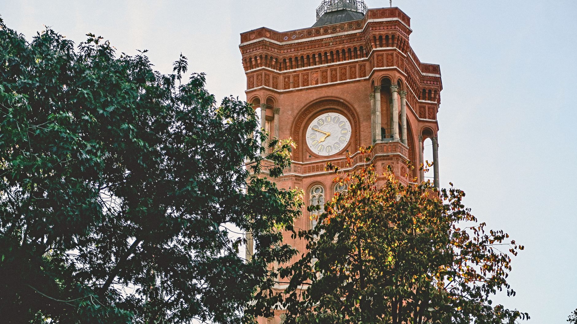 Historic Rotes Rathaus clock tower in Berlin with red brick and trees in foreground.