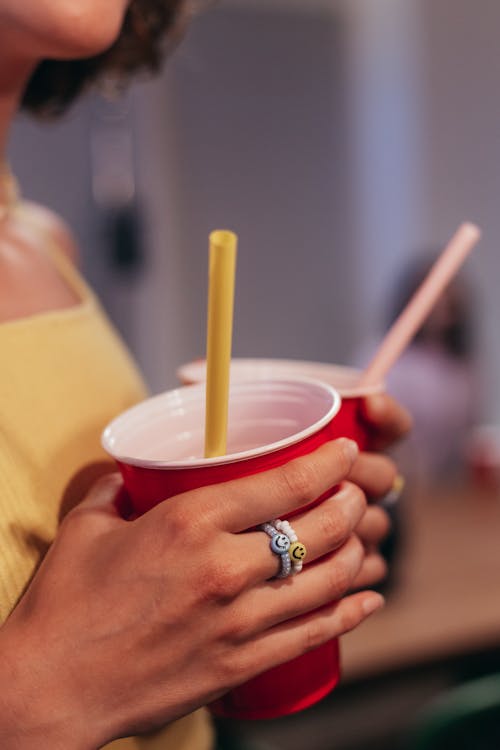 Person Holding Red Plastic Cup with Straw