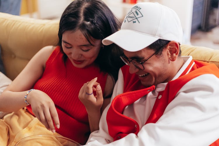 Young Couple Sitting On A Couch And Smiling 