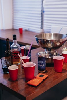 Party scene with drinks, red cups, and a tetris-themed gadget on a wooden table.