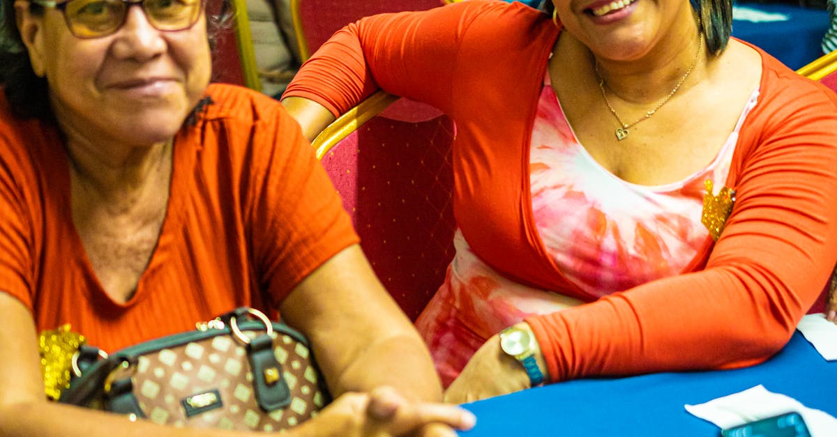 Smiling women enjoying a community gathering indoors, surrounded by people.
