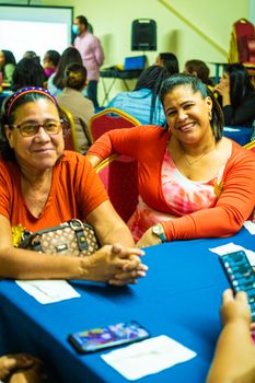 Smiling women enjoying a community gathering indoors, surrounded by people. - Fotografer Sidoarjo