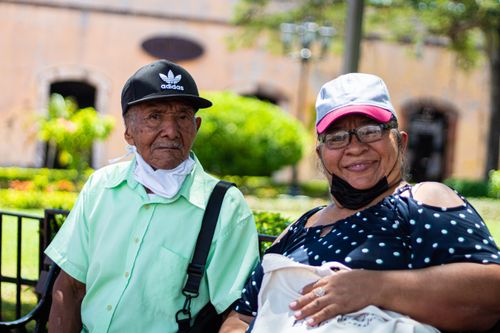Free Senior couple sitting outdoors wearing face masks during daylight. Stock Photo