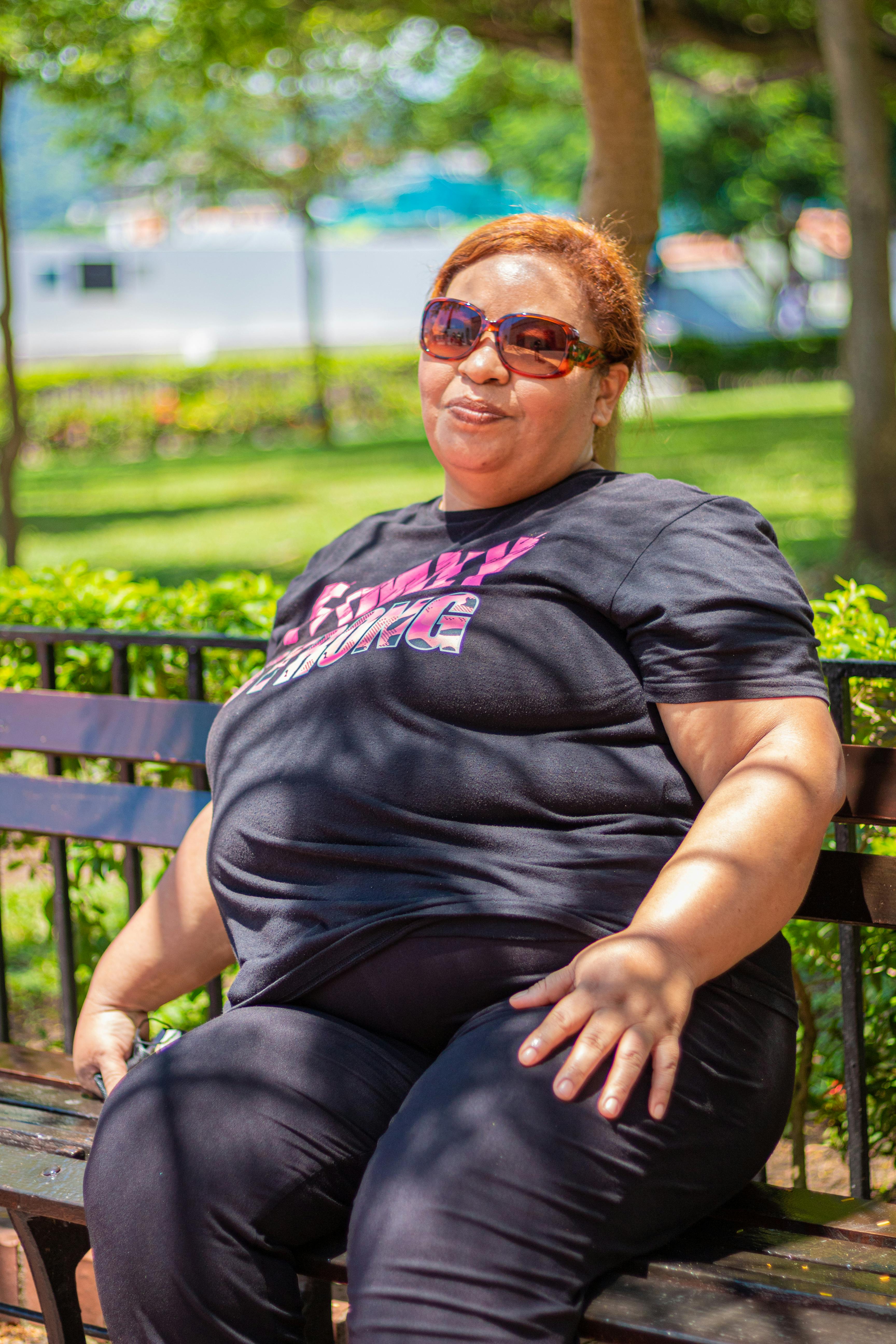 a woman wearing black shirt sitting on a wooden bench while smiling at the camera