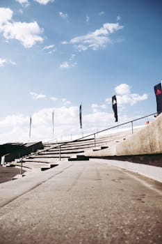 Modern amphitheater stairs with flags against a bright blue sky, creating a dynamic urban scene.