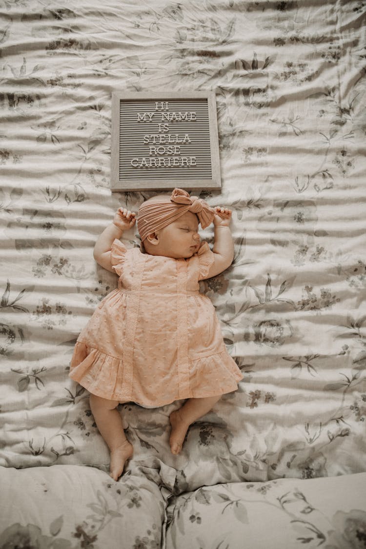 Top View Of A Baby Girl Sleeping Below A Letter Board