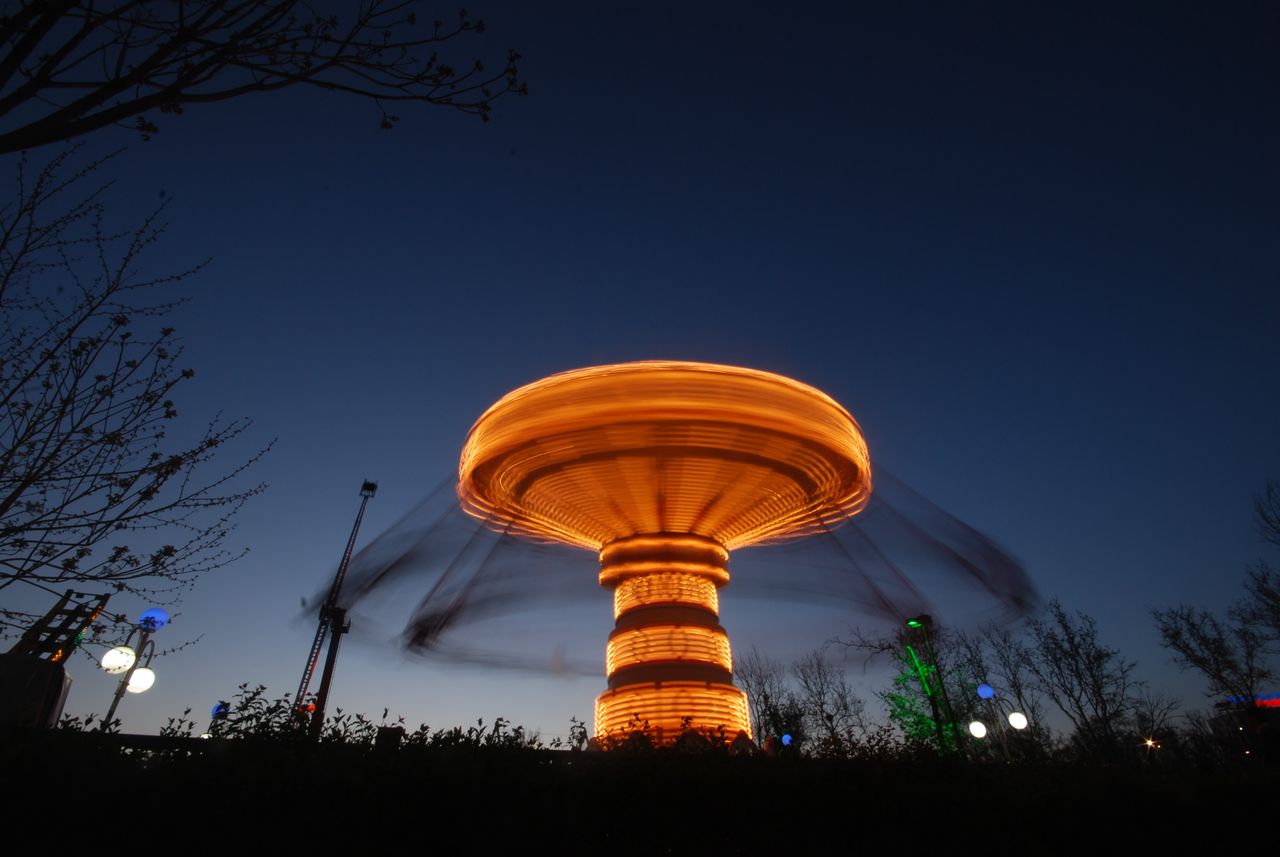 long exposure photo of an illuminated swing ride at night capturing it