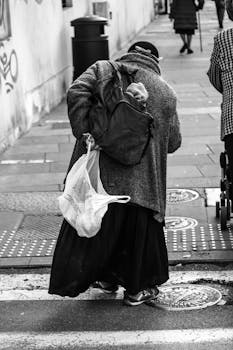 Black and white photo of an elderly woman crossing the street in Brescia, Italy.