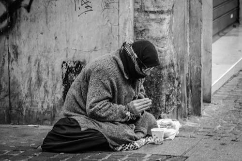Free Grayscale Photography of Man Praying on Sidewalk With Food in Front Stock Photo