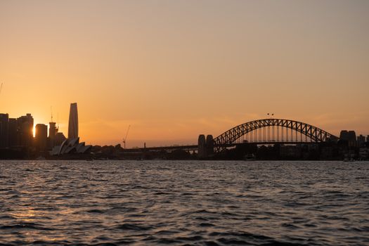 Stunning view of Sydney Harbour Bridge and Opera House at sunset reflecting on the water.
