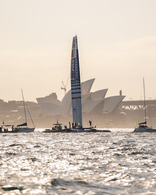 An F50 Foiling Catamaran in Between Two Boats