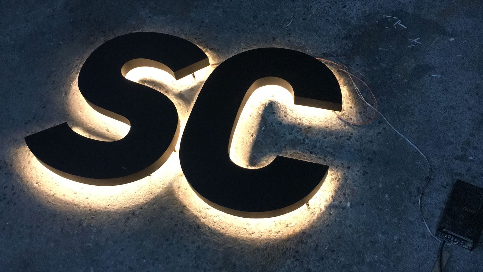 Illuminated LED backlit letters mounted on a wall, glowing effect