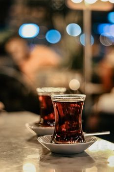 Elegant Turkish tea in traditional glasses with a blurred bokeh background in a cozy setting.