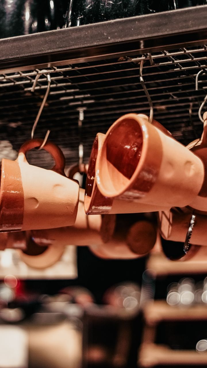 dark wood wall-mounted mug rack holding colorful ceramic coffee mugs