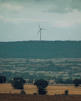 A peaceful rural scene featuring a solitary wind turbine against a vast countryside backdrop.