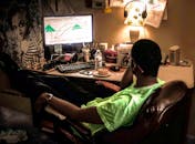 一名男子在配有电脑、台灯和国际象棋的舒适家庭办公室里放松身心，享受休闲时光