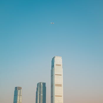 A commercial airplane flies over tall skyscrapers on a clear day, offering ample copy space.