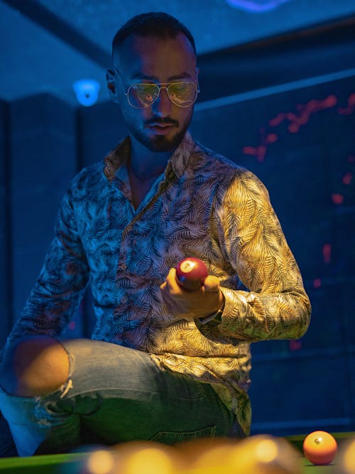 A Man Looking at the Billiard Ball that He is Holding