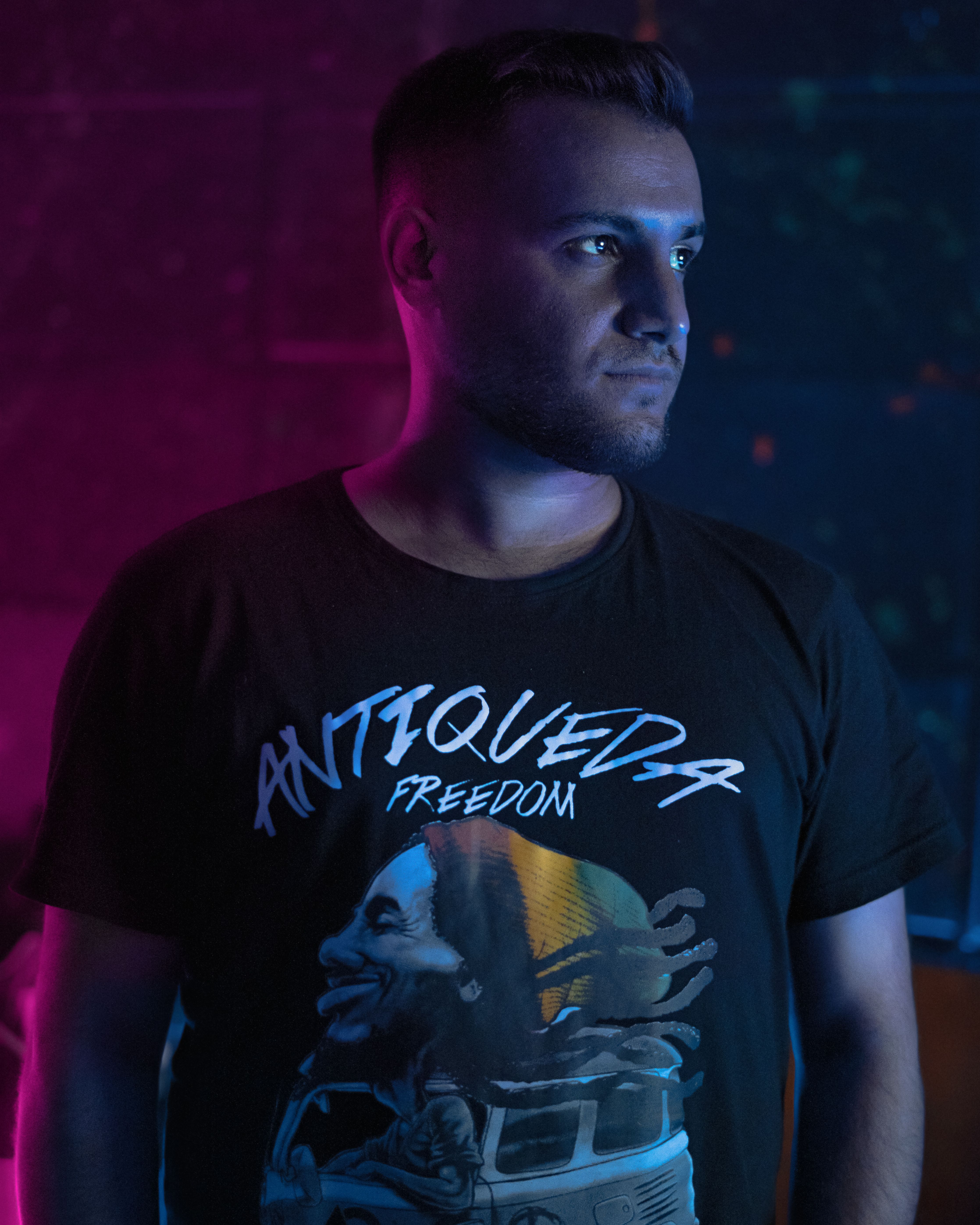 A modern, stylish portrait of a young man standing against a vibrant, colorful background in creative lighting.