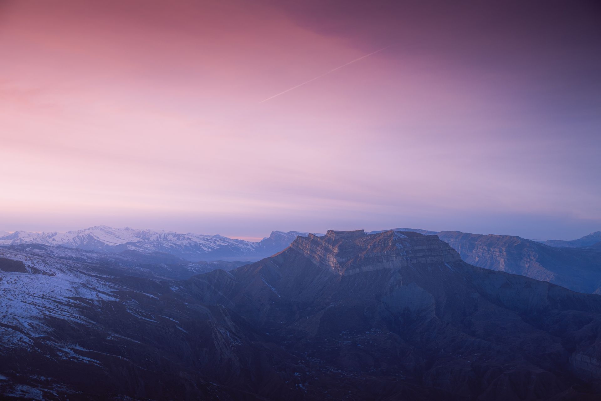 A breathtaking aerial view of a mountain range during twilight with a vivid sky