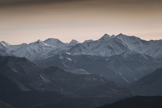 Calm and serene snow-draped mountains under a twilight sky, showcasing natural beauty.