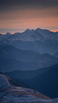 A stunning view of snow-capped mountains under a twilight sky, offering a serene landscape scene.