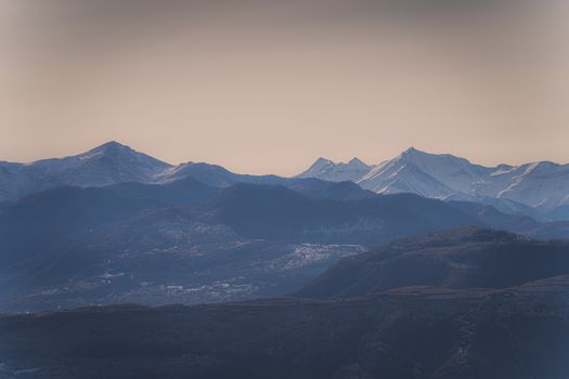 A peaceful view of snow-capped mountain range at dusk with soft pastel skies.