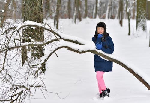 Woman in Blue Jacket Standing on Snow Covered Ground