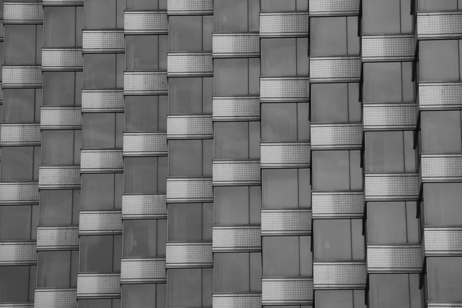 Close-up of a modern building facade with repetitive geometric window patterns in black and white.