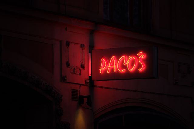 Enseigne lumineuse rouge éclairant l'angle d'une rue la nuit