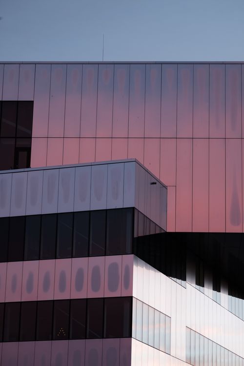 Free A contemporary building exterior with reflective glass panels showcasing a beautiful sunset glow. Stock Photo