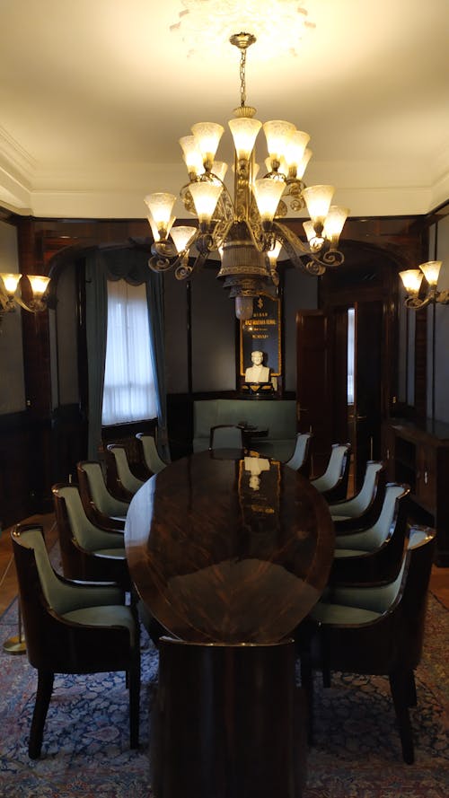 Brown Shiny Wooden Oval Table and Chandelier in a Room