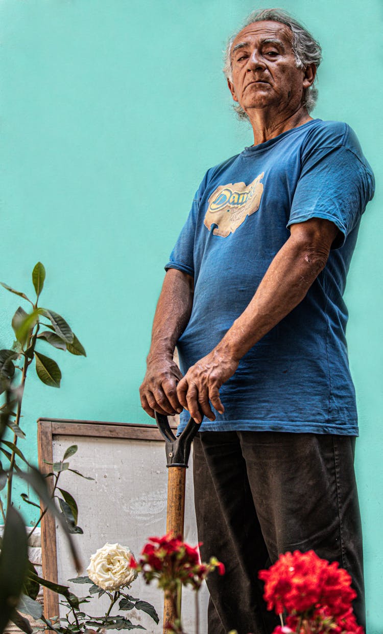 Elderly Man In Blue Shirt Holding A Shovel