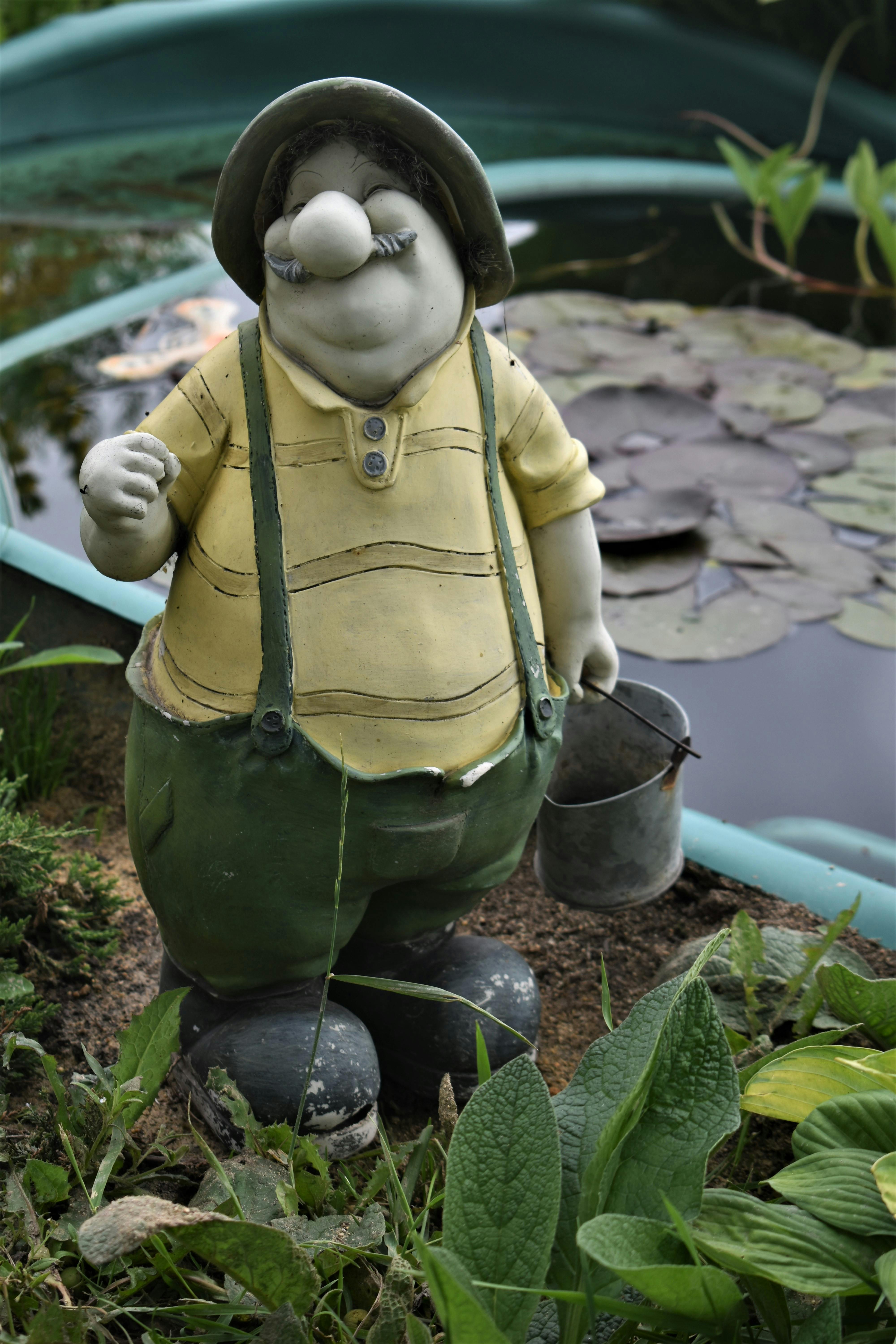 Whimsical garden gnome statue by a pond, ideal for yard decoration.