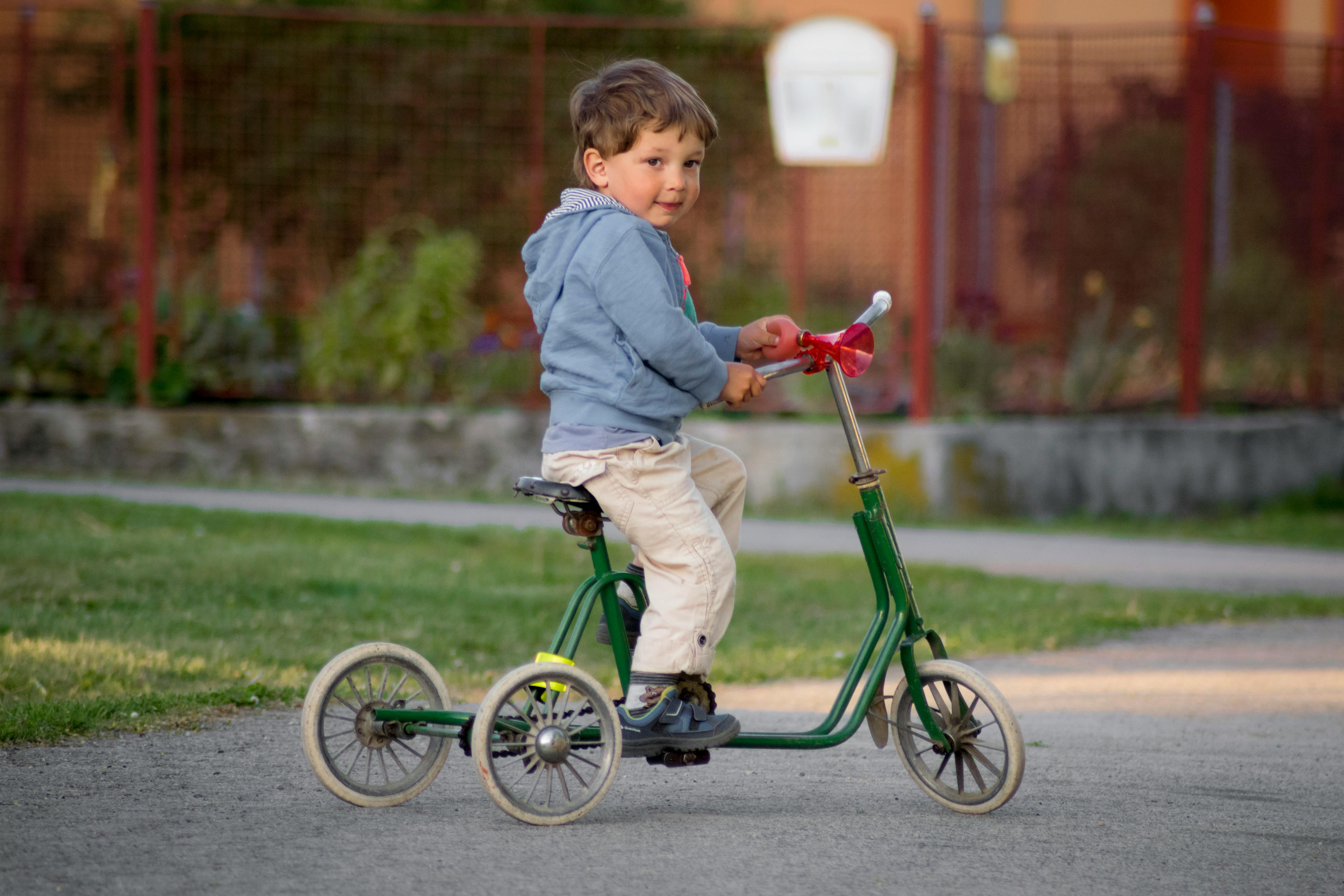 Little boy riding a green bike. | Photo: Pexels